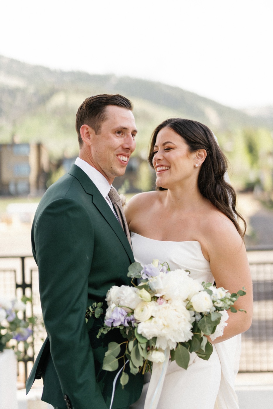 Maddy and Kody laughing, she holds a bouquet of white peonies and lavender sweet peas